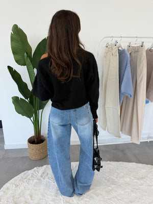 Elvya trui – zwarte one-shoulder dames trui, achteraanzicht gestyled met jeans